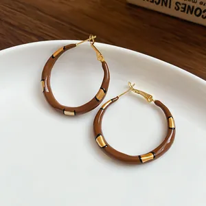 Nahaufnahme von braunen Vintage-Hoop-Ohrringen mit goldenen Akzenten auf Teller