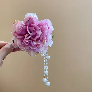 Macro detail view of an elegant pink fabric flower hair clip with decorative pearl tassels