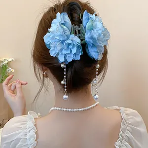 Detail view of a blue fabric flower hair claw clip featuring elegant pearl tassels.