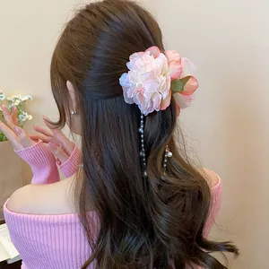 Elegant pink fabric flower hair claw clip with pearl tassels shown on model's hair detail.