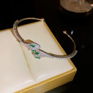 Primer plano detallado de un brazalete abierto con forma de serpiente y circonitas