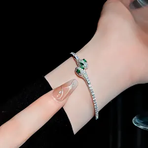 Primer plano de un brazalete de serpiente plateado con ojos verdes y circonitas