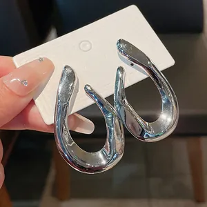 Detailed close-up showing the unique twisted shape of silver metallic hoop earrings