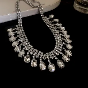 Detailed macro shot of vintage-inspired square rhinestone fringe necklace on black surface.