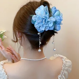 Elegant blue fabric flower hair clip with dangling pearl tassels worn in a stylish updo