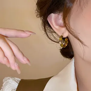 Close-up detail showing real gold-plated minimalist round hoop earrings with amber beads
