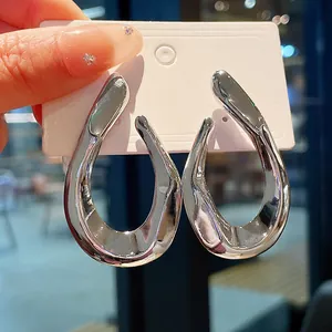 Detail of chunky silver distorted metal earrings with minimalist abstract design.