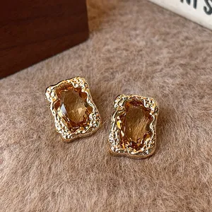 Macro view showing the textured gold-plated edges and amber faceted stone of luxury earrings.