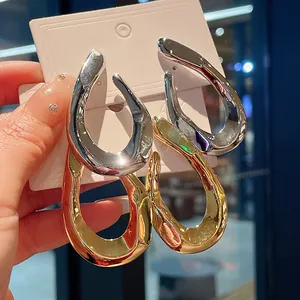 Detailed close-up of chunky twisted metal hoop earrings in shiny silver and gold finishes