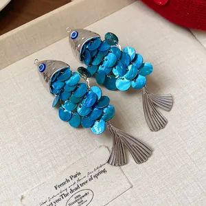 Detailed macro view of two vintage shell fish-shaped hair clips with blue sequins.