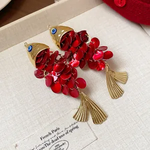 Close-up of retro ethnic style shell fish-shaped hair clip with red and gold finish