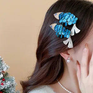 Detail of fish-shaped hair clips with blue scales and silver tassels on brown hair