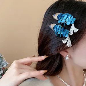 Close-up of blue fish-shaped hair clips with sequin scales on a woman's hair.