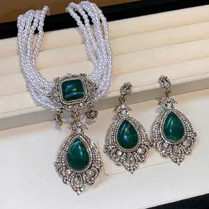 Vintage luxury jewelry set featuring multi-strand pearls and green teardrop stones