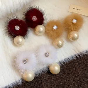 Dettaglio di eleganti orecchini di peluche con zirconi e perle in vari colori