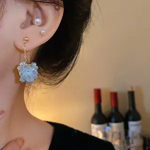 Gros plan de boucles d'oreilles à pampilles fleurs de perles sur l'oreille.