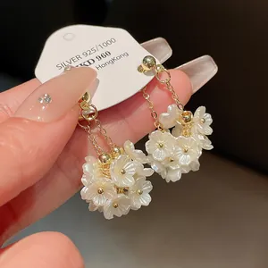 Vue détaillée de boucles d'oreilles pendantes avec fleurs en perles et chaînes dorées