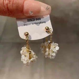 Détail de boucles d'oreilles fleuries vintage avec des pétales de nacre blanche