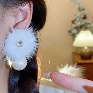 Dettaglio ravvicinato di orecchino in peluche bianco con zircone e goccia di perla