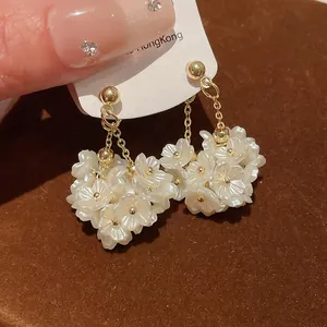 Détail rapproché de boucles d'oreilles vintage à pampilles de fleurs blanches nacrées et or