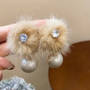 Dettaglio di eleganti orecchini a perno con zircone e perla peluche per l'autunno inverno.