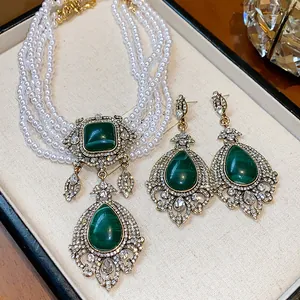 Detailed macro view of vintage pearl necklace and earrings set with green gemstones