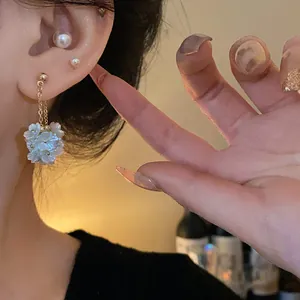 Vue macro détaillée d'élégantes boucles d'oreilles pampilles en fleurs de perles blanches