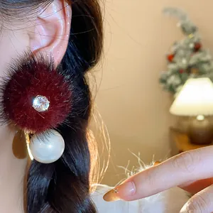Dettaglio degli eleganti orecchini in pelliccia bordeaux con zircone e perla bianca