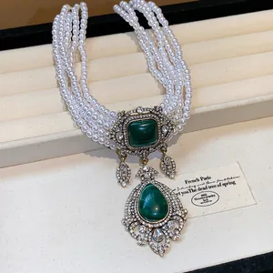 Detailed view of vintage multi-strand pearl necklace with green teardrop pendant.