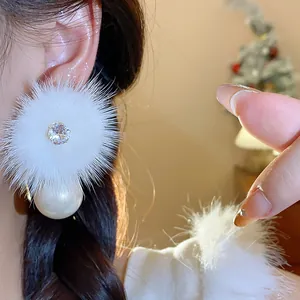 Dettaglio ravvicinato di orecchini in peluche bianchi con zircone e perla pendente