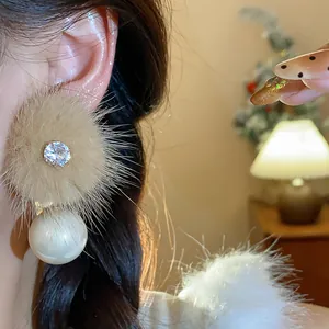 Primo piano di eleganti orecchini di perle di peluche con zircone scintillante sull'orecchio.