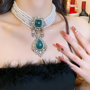 Close-up of vintage multi-strand pearl choker with elegant green drop pendant and crystals.