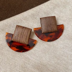 Close-up of retro square resin stud earrings with a tortoiseshell half-moon pattern
