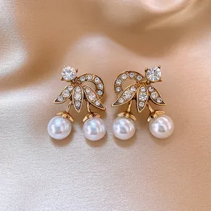 Vista dettagliata di eleganti orecchini vintage in oro con cristalli e perle bianche