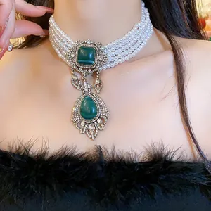 Close-up detail of a vintage multi-strand pearl choker with a green waterdrop pendant