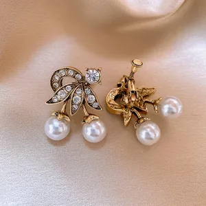 Dettaglio orecchini vintage francesi in oro e perle con fiocco di cristallo lucido