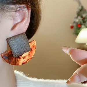 Close-up of geometric resin stud earrings with tortoiseshell and wood-texture finish