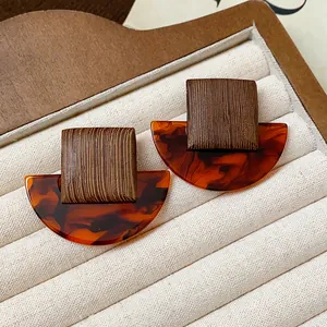 Close-up view of vintage geometric earrings with wood texture and tortoiseshell resin pattern.