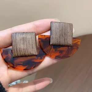 Close-up of retro square wood-textured resin earrings with amber tortoiseshell finish
