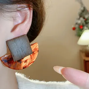 Close-up detail of vintage square and tortoiseshell resin stud earrings worn on ear