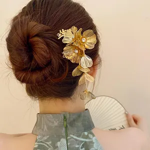 Close-up view of a gold flower hair pin with rhinestones and tassels worn on a hair bun