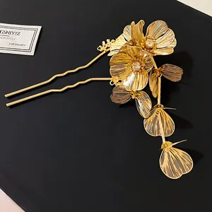 Close-up of gold metal flower hair fork with sparkling rhinestones and delicate tassels.