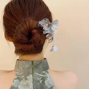 Elegant silver metal flower hairpin with tassels and rhinestones worn on a hair bun