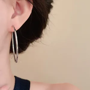 Detailed close-up showing minimalist large silver hoop earrings worn on a model's ear