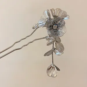 Detailed macro shot of silver floral hair stick with rhinestone and dangling tassels.