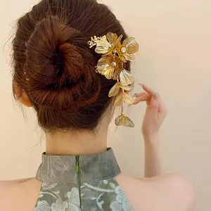 Close-up of golden floral metal hair stick with rhinestones and tassel