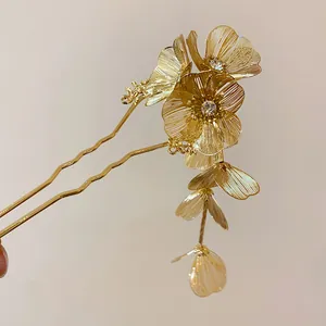 Close-up of elegant gold flower hair fork with sparkling rhinestones and dangling metal petals