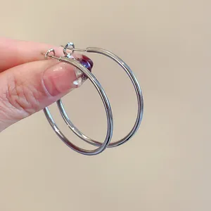Macro view of large silver-toned hoop earrings with a minimalist and smooth round design