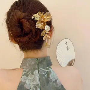 Detailed view of an elegant gold floral hair pin with sparkling rhinestones and tassels.