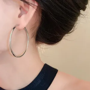 Close-up of large minimalist silver hoop earrings on model, stylish and oversized design.